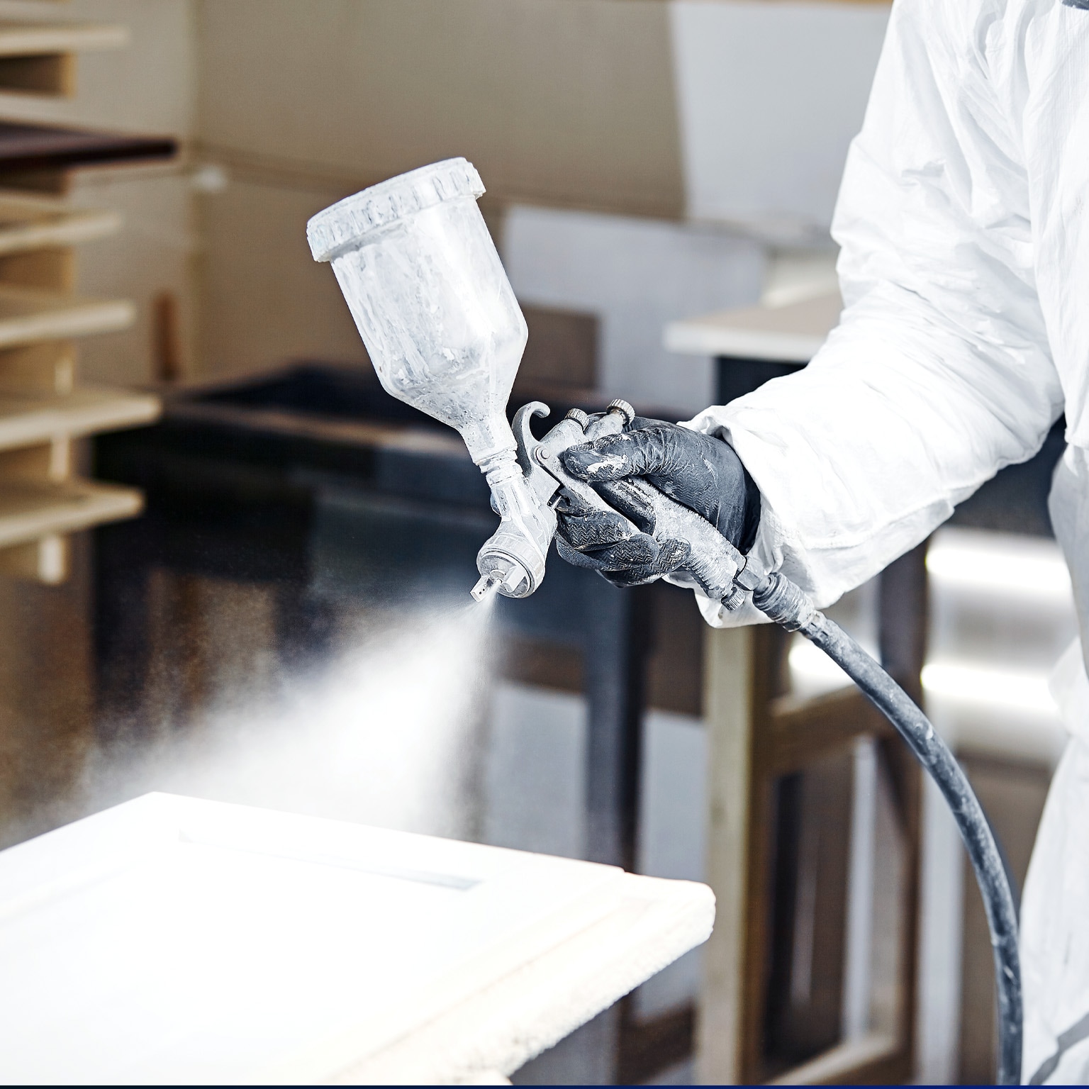 Close-up of industrial worker using paint gun for applying paint