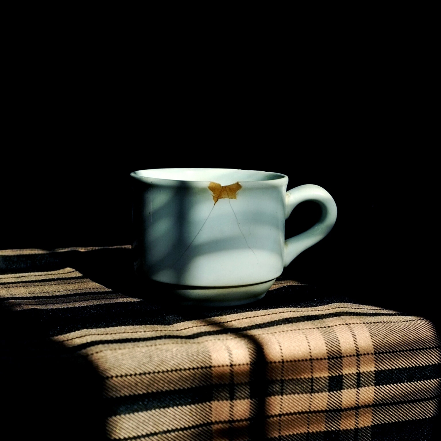 Close-Up Of Broken Coffee Cup Against Black Background